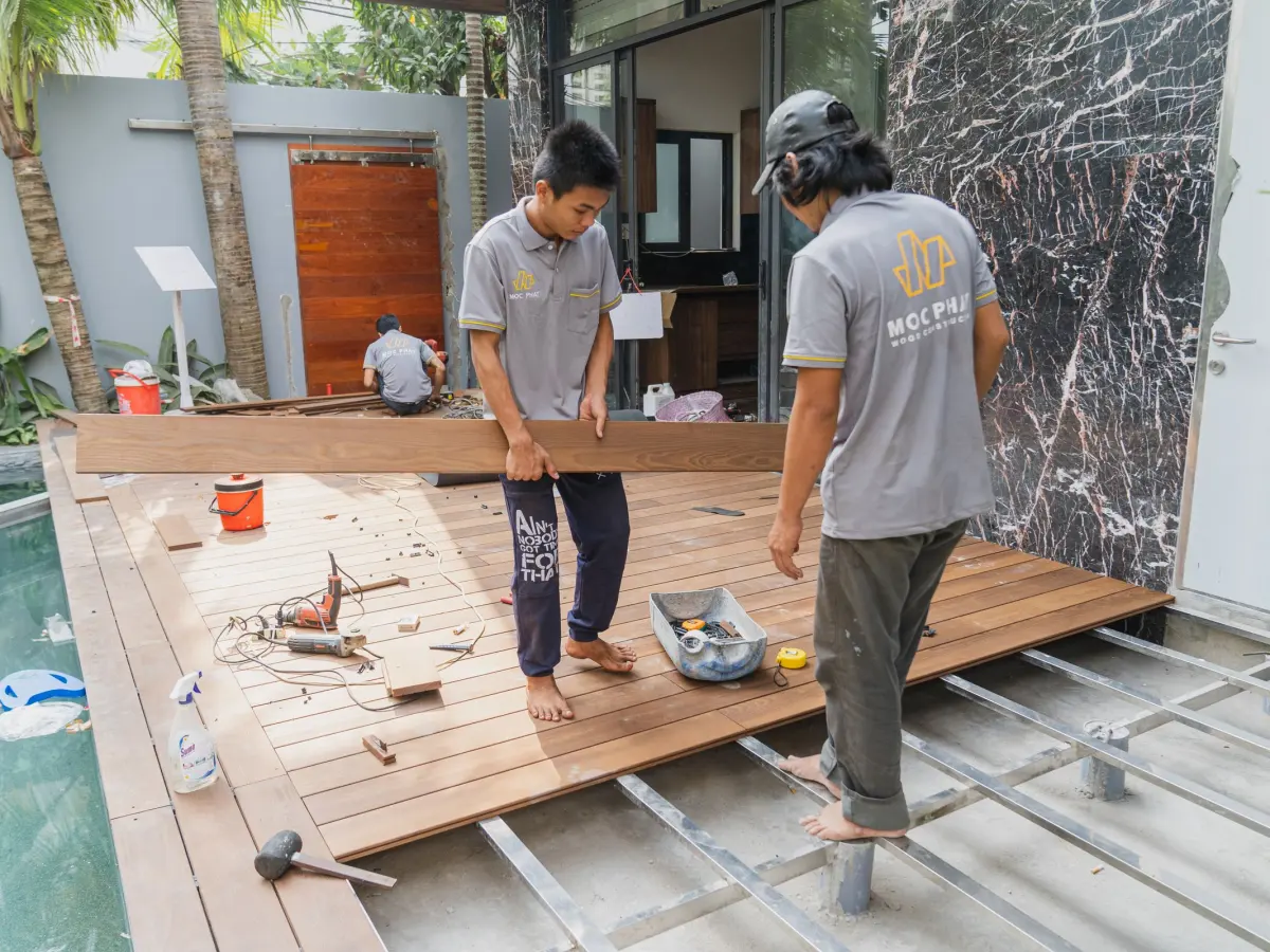 Installation de terrasse en bois à Antibes : artisans posant les lames d'une terrasse en bois au bord d'une piscine